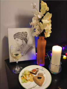 Memorial to Hypatia with candle, flowers, wine and food offerings before an image of her